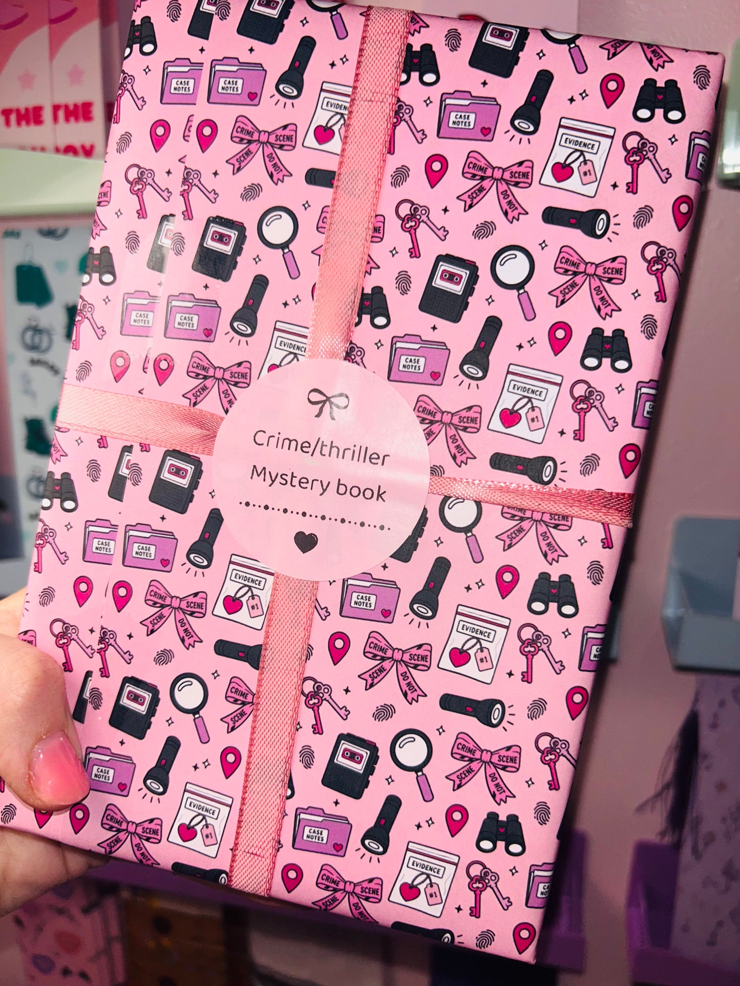 Pink crime/thriller mystery book with patterned accessory icons