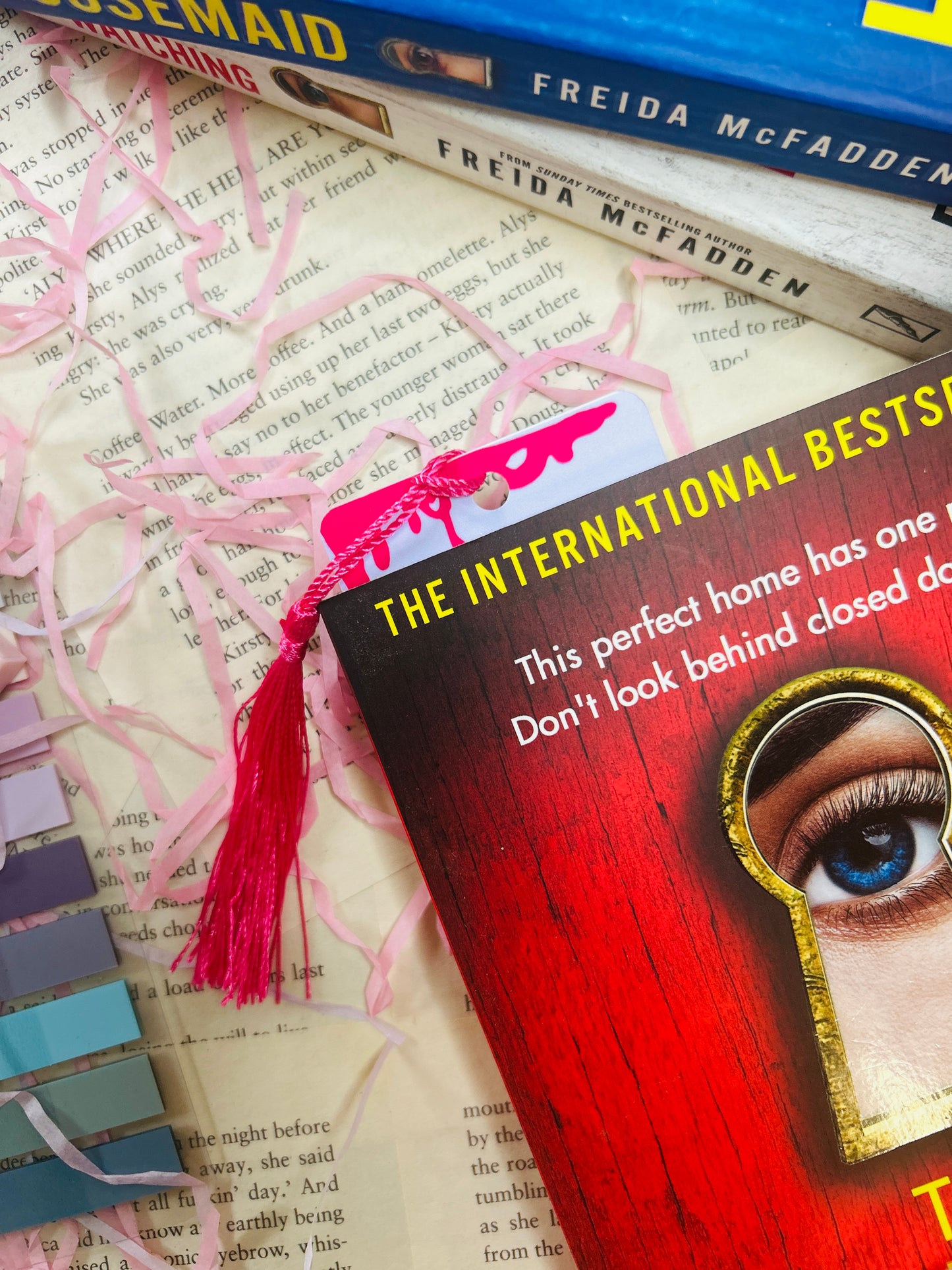 True crime bookmark with pink tassel, red-and-pink keyhole graphic on pale card
