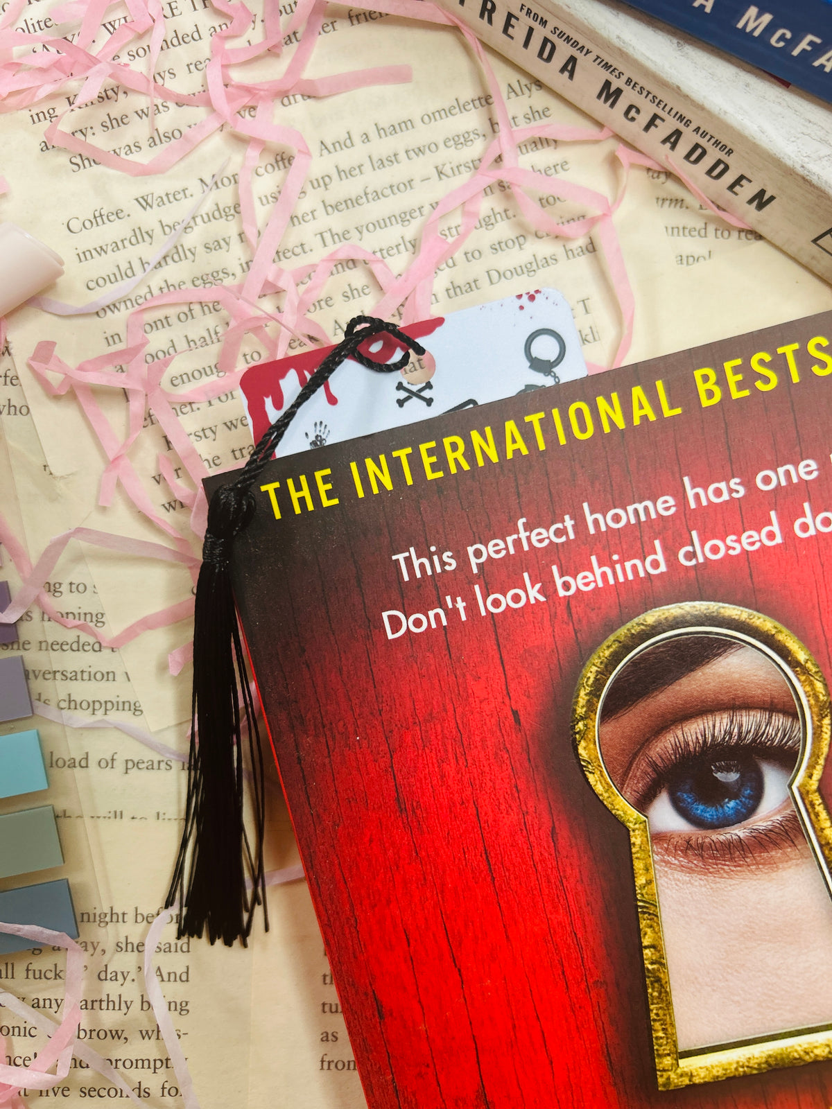 Thriller bookmark with red lettering, gold keyhole eye graphic, and black tassel