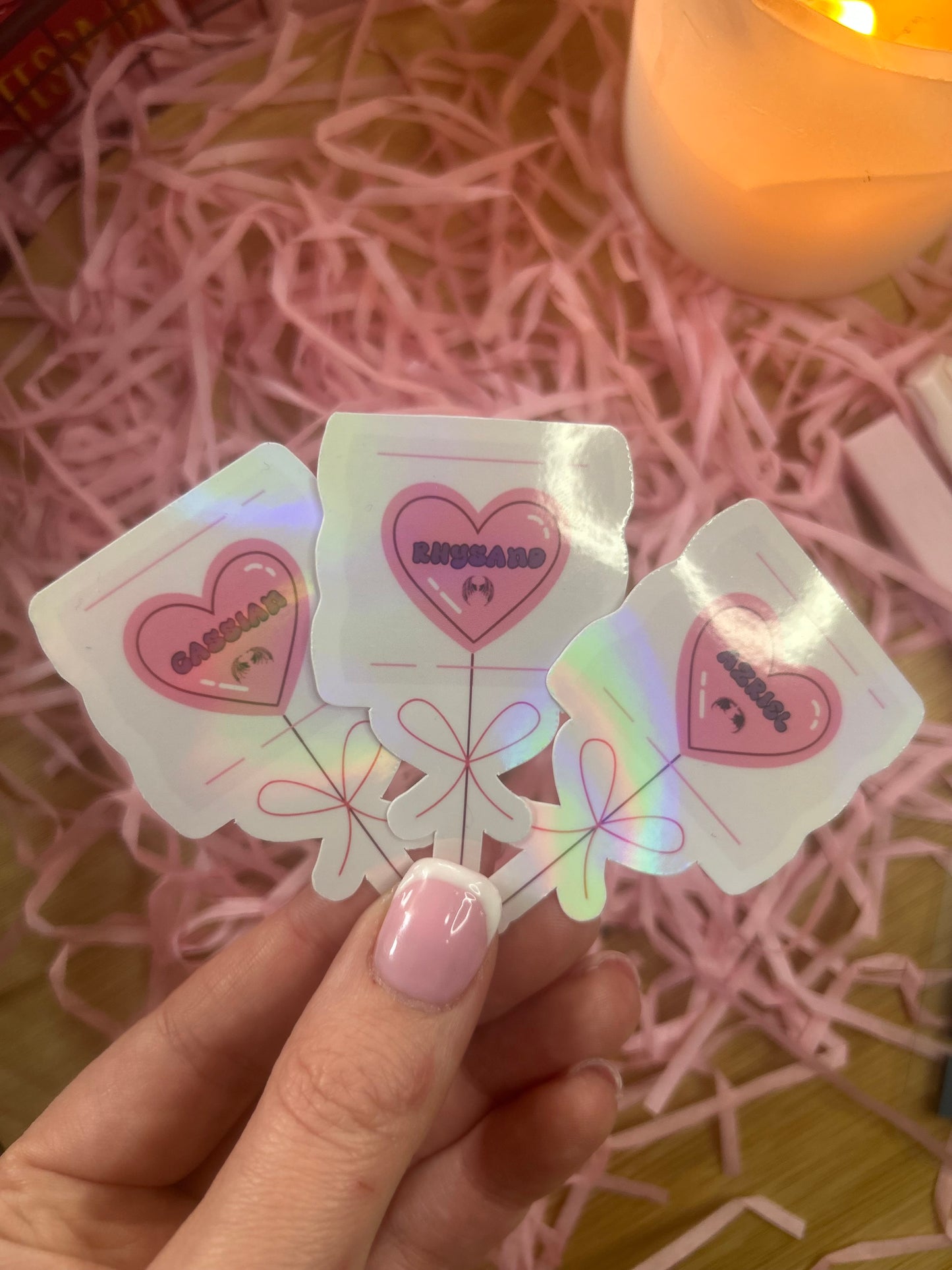 Holographic ACOTAR candy heart balloon stickers featuring Rhysand, Cassian, and Azriel. Perfect bookish merch for fantasy lovers, ideal for decorating laptops, water bottles, and journals.