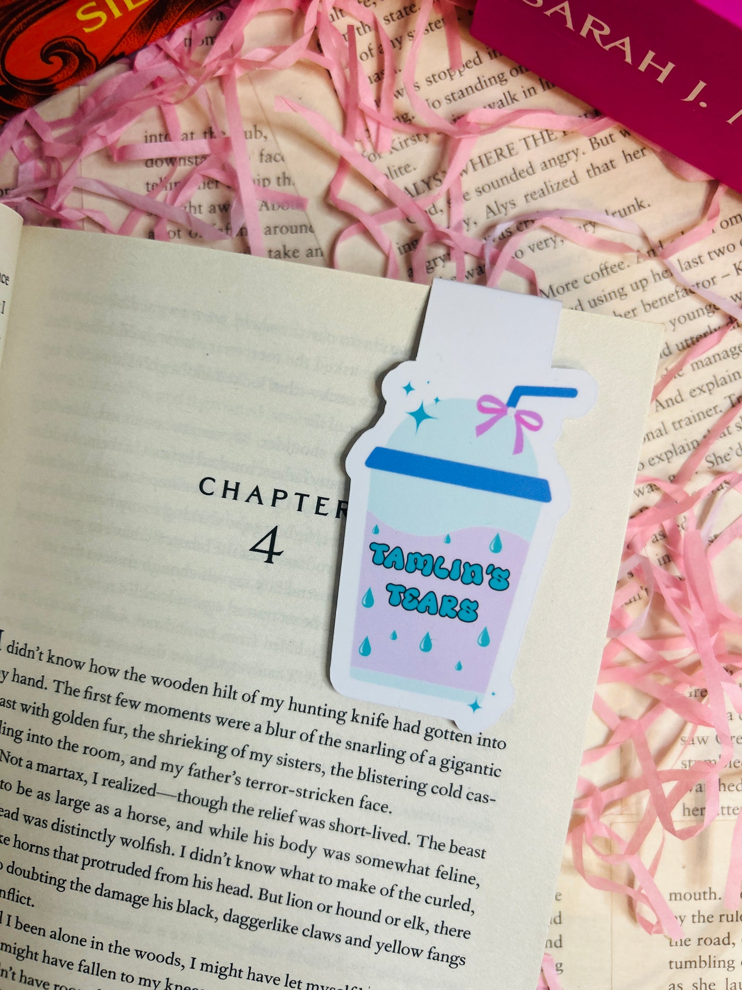 Magnetic bookmark shaped like a takeaway cup labelled “Tamlin’s Tears,” clipped to a fantasy book page with pink shredded paper in the background.