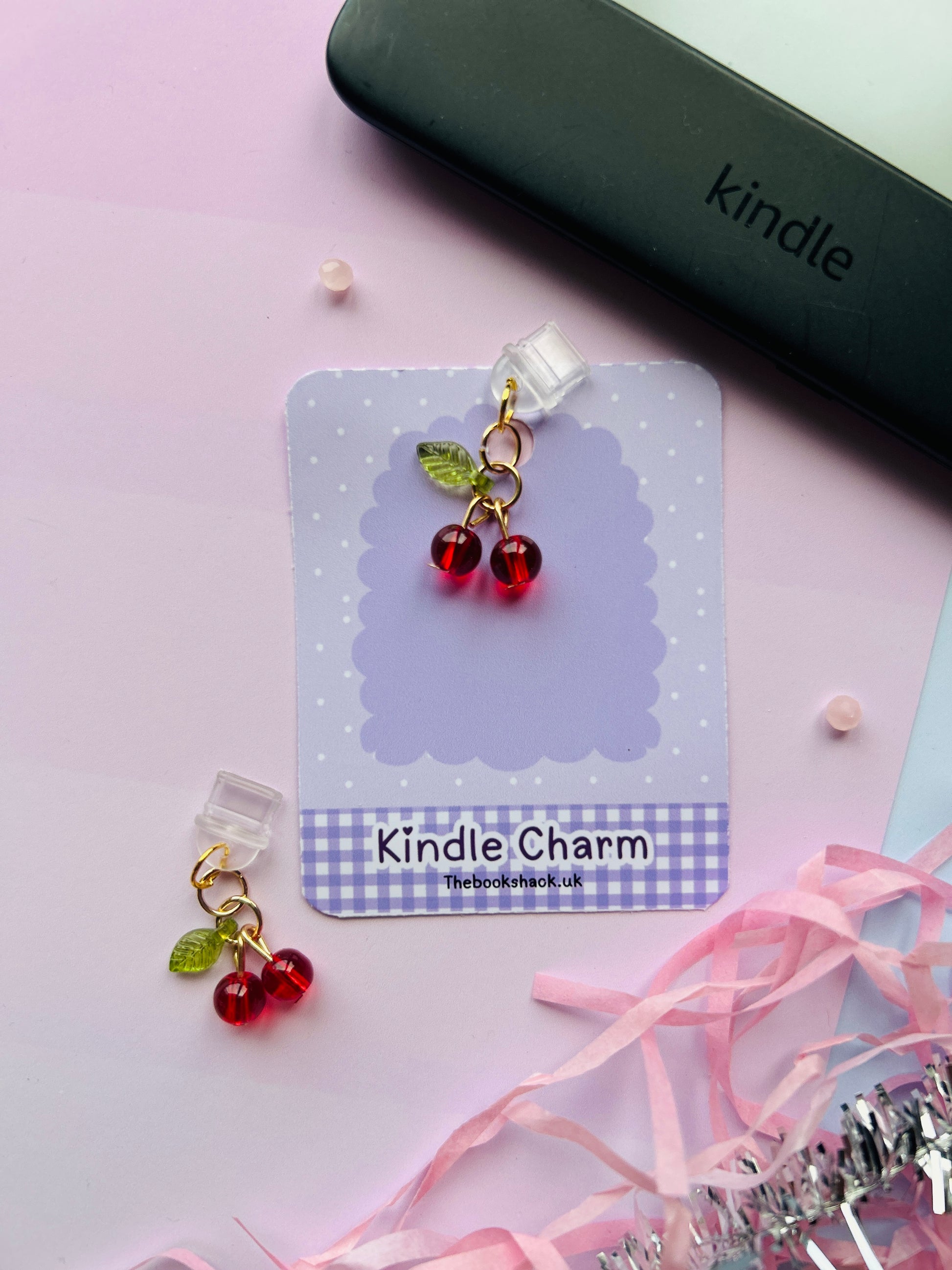 Cherry Kindle charm attached to a clear plastic Type-C dust plug, displayed with backing card and holographic packaging, with optional white letter charm.