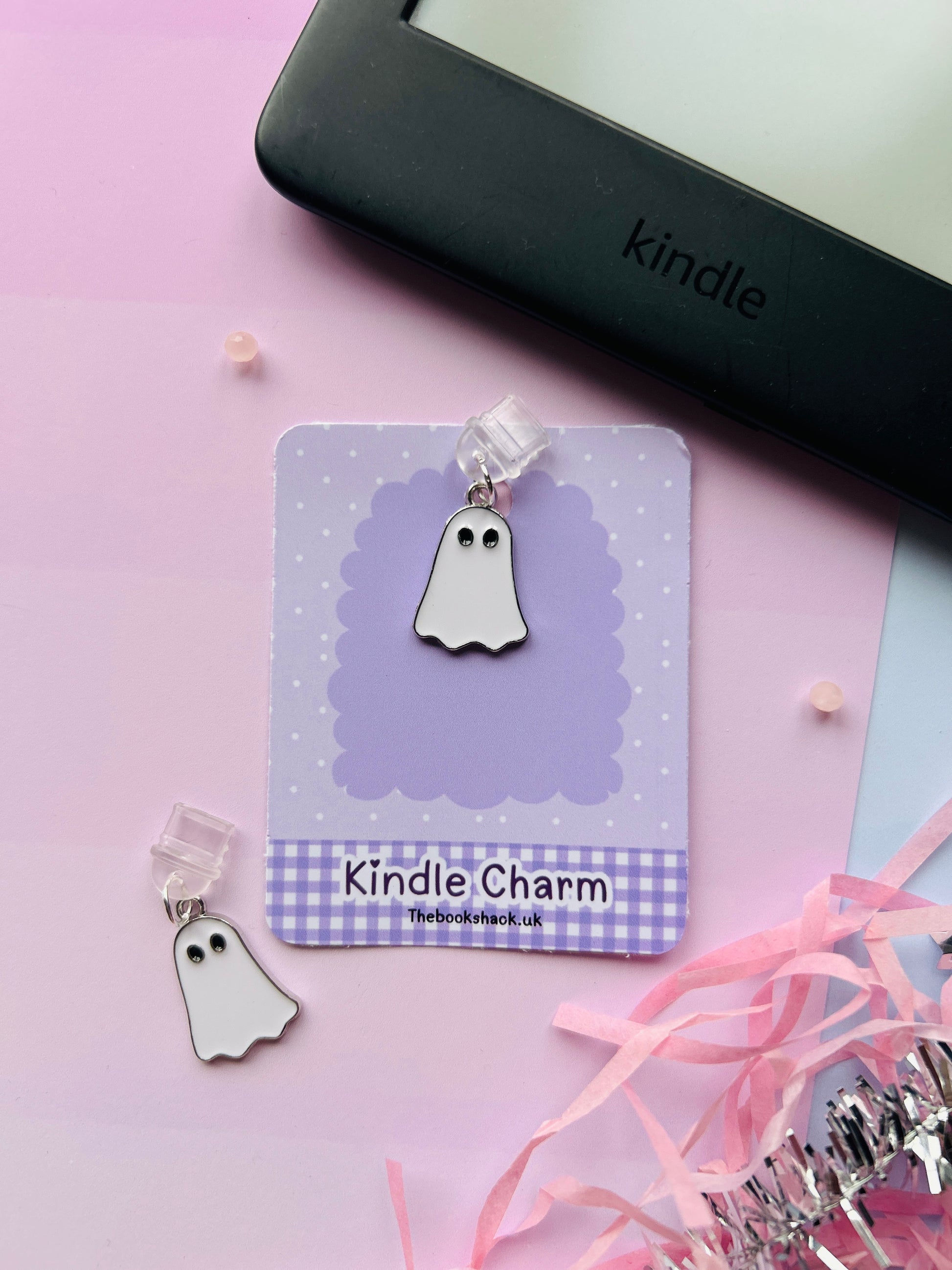 white ghost Kindle charm attached to a clear plastic Type-C dust plug, displayed with backing card and holographic packaging, with optional white letter charm.