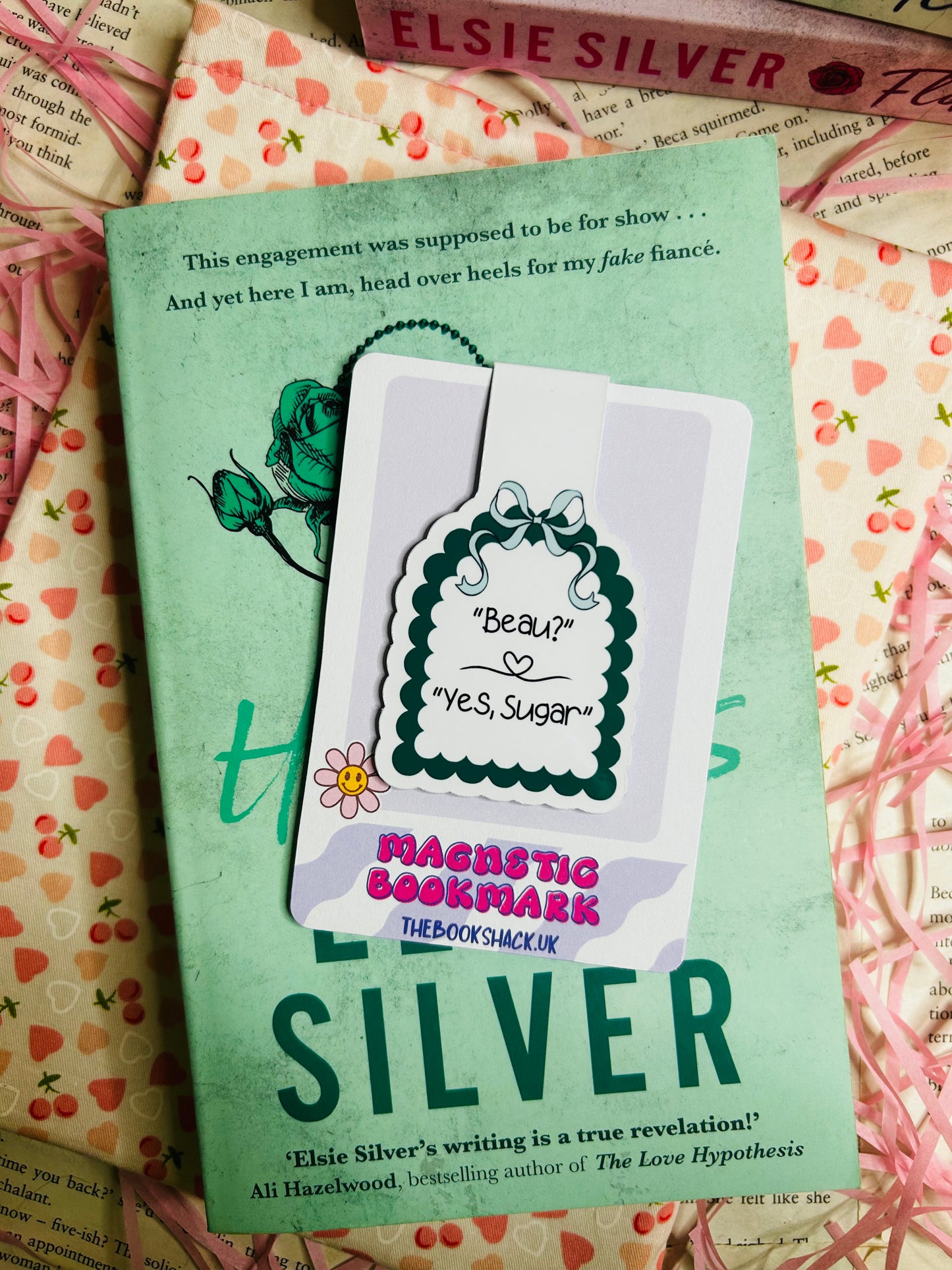 Magnetic bookmark displaying the quote 'Beau? Yes, Sugar' with a green scalloped border and floral accent, placed atop Elsie Silver's romance novel 'Heartless.'