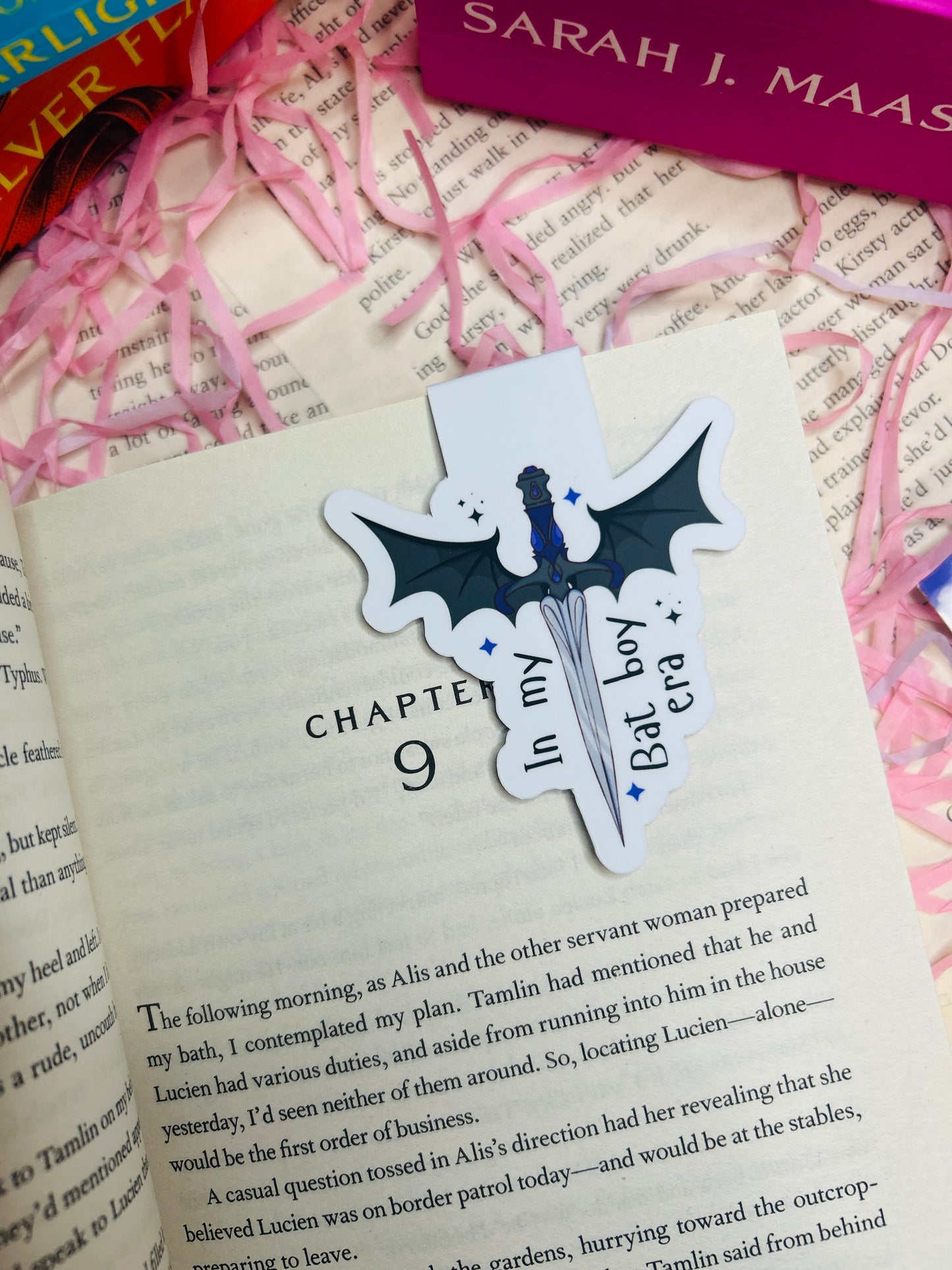 Bat-shaped bookmark on a book with pink ribbons and a visible title page.