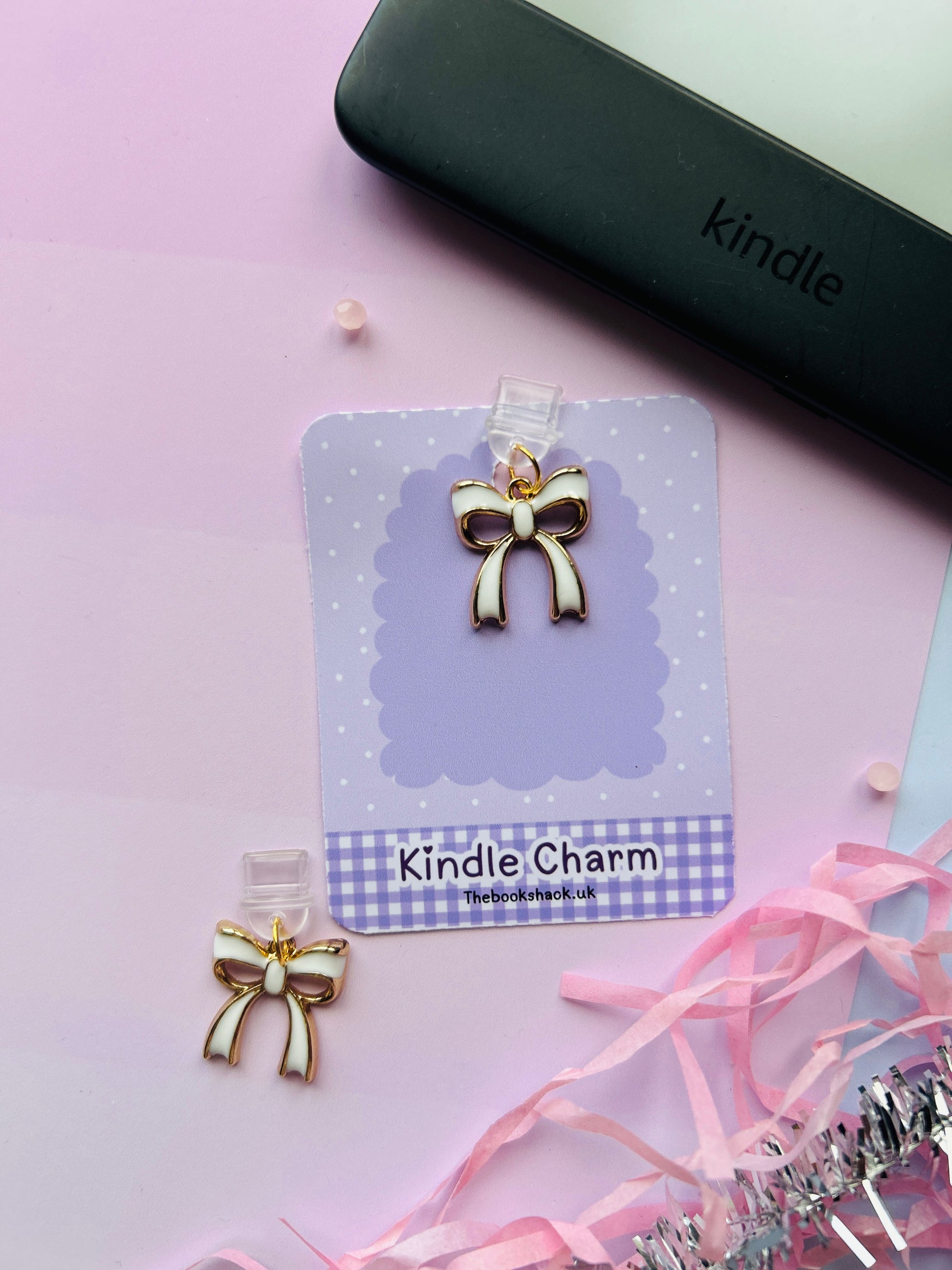 white bow Kindle charm attached to a clear plastic Type-C dust plug, displayed with backing card and holographic packaging, shown with optional white letter charm.