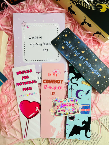 A colourful display of our Oopsie Mystery Grab Bag contents, featuring five unique bookish items such as bookmarks and stickers with minor imperfections.