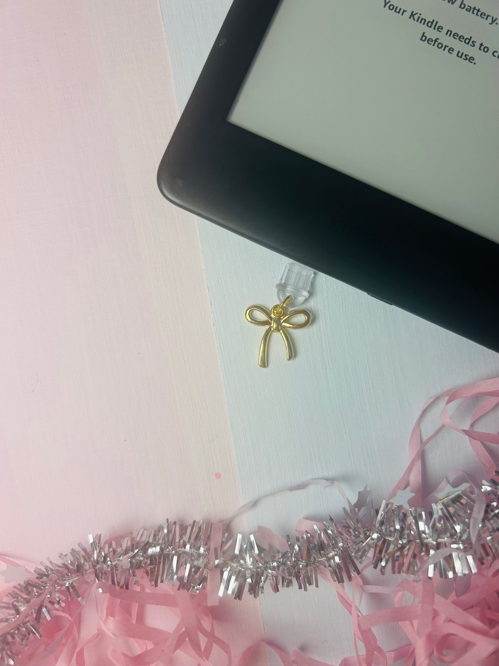 Gold bow USB-C dust plug charm with small looped ribbon detail