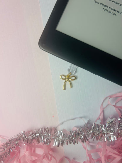 Gold bow USB-C dust plug charm with small looped ribbon detail