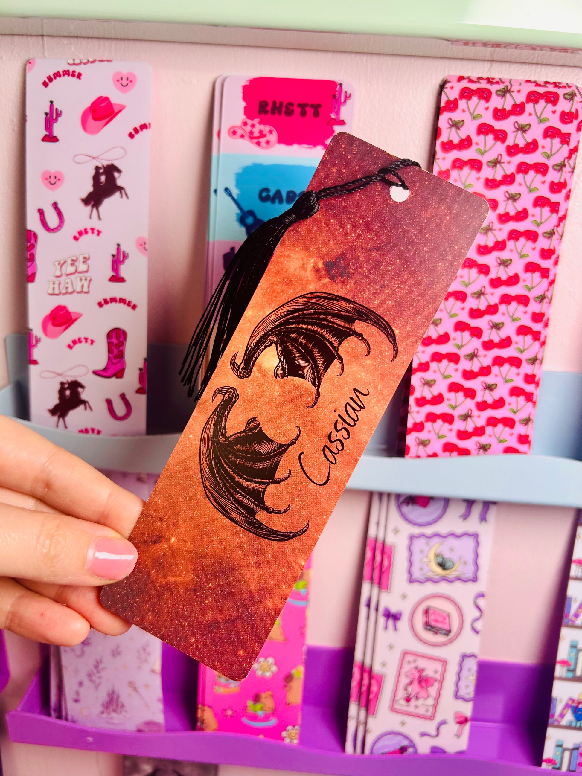 Orange glitter bookmark with face art and 'I will find you' quote, held in hand