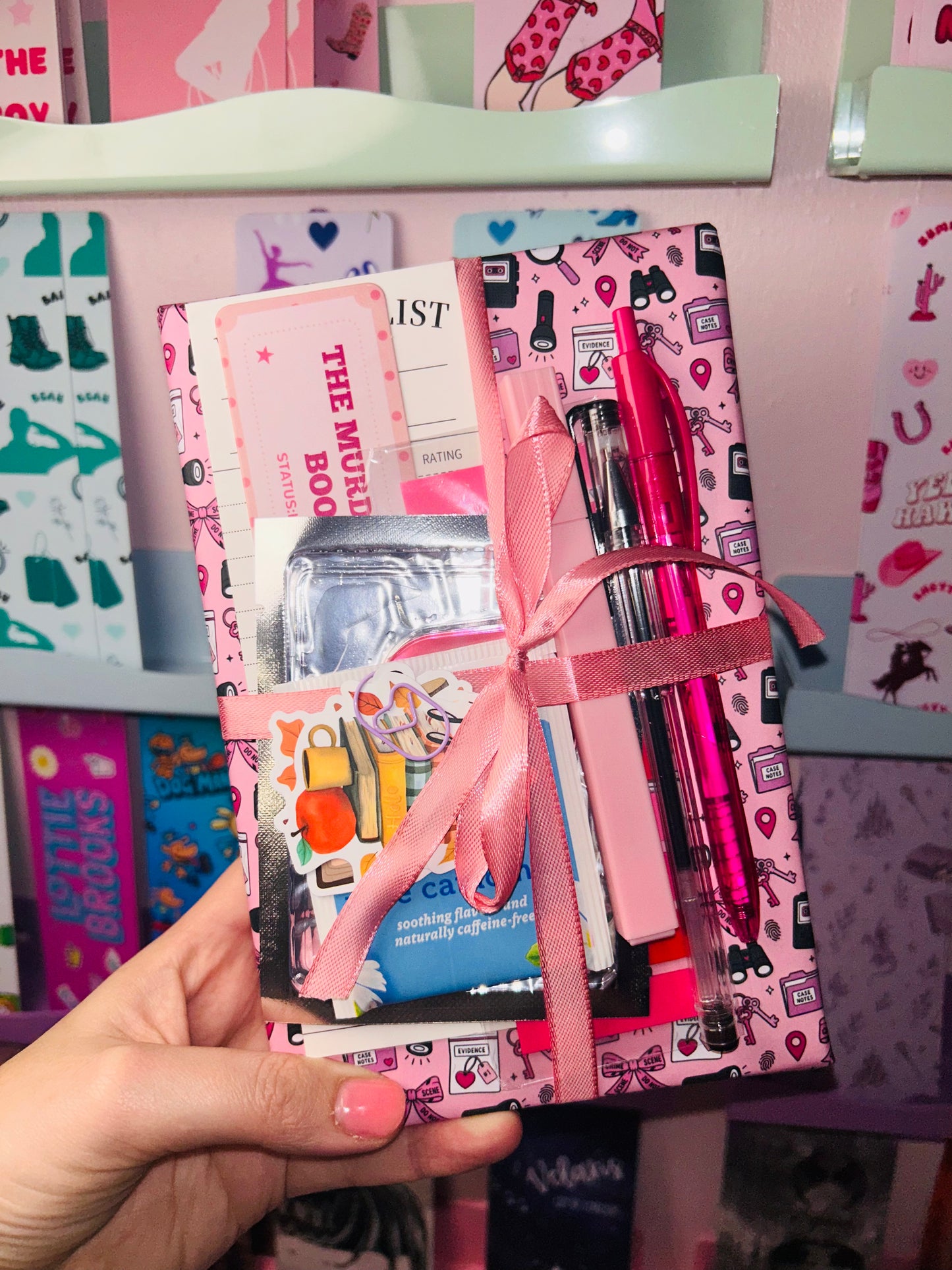 Pink mystery book gift bundle with ribbon-tied books and pen accessories