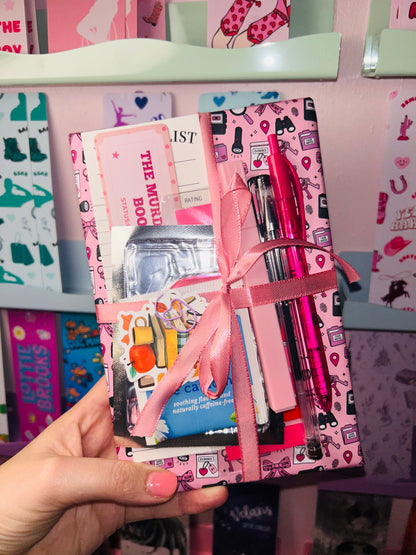 Pink mystery book gift bundle with ribbon-tied books and pen accessories