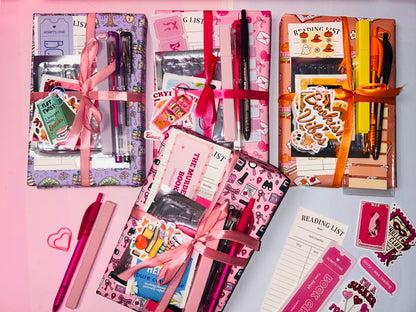 Assorted mystery book gift bundles with pens and stationery, in pink, purple, and orange