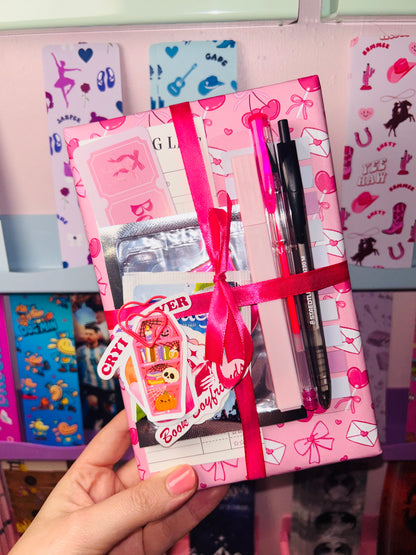 Pink mystery book gift bundle with ribbon and three packaged pen sets