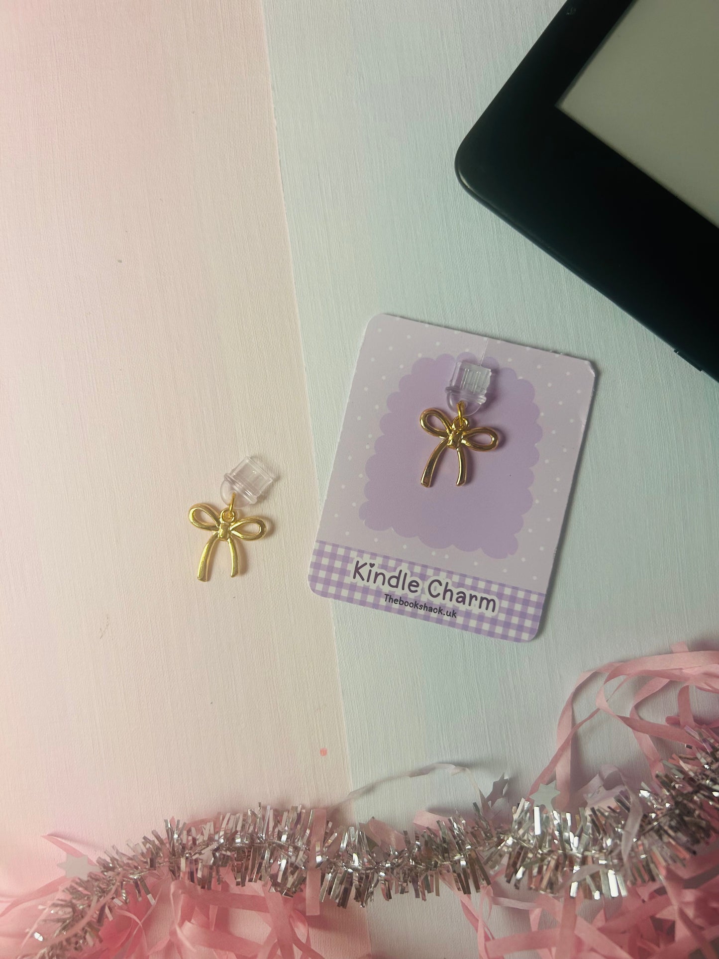 Gold bow USB-C dust plug charm on purple backing card