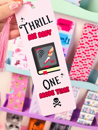 Close-up pink bookmark with tassel, TV-style crime graphic, 'THRILL ME BABY' text.