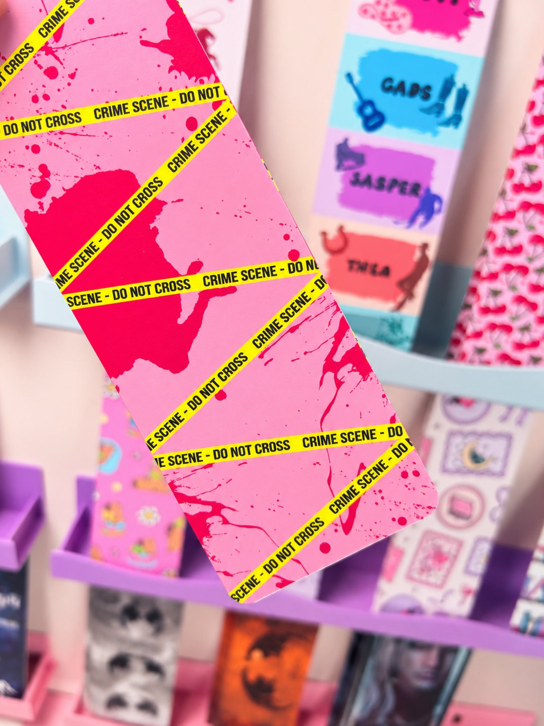 Angled pink crime-scene bookmark with neon tape stripes and pink tassel
