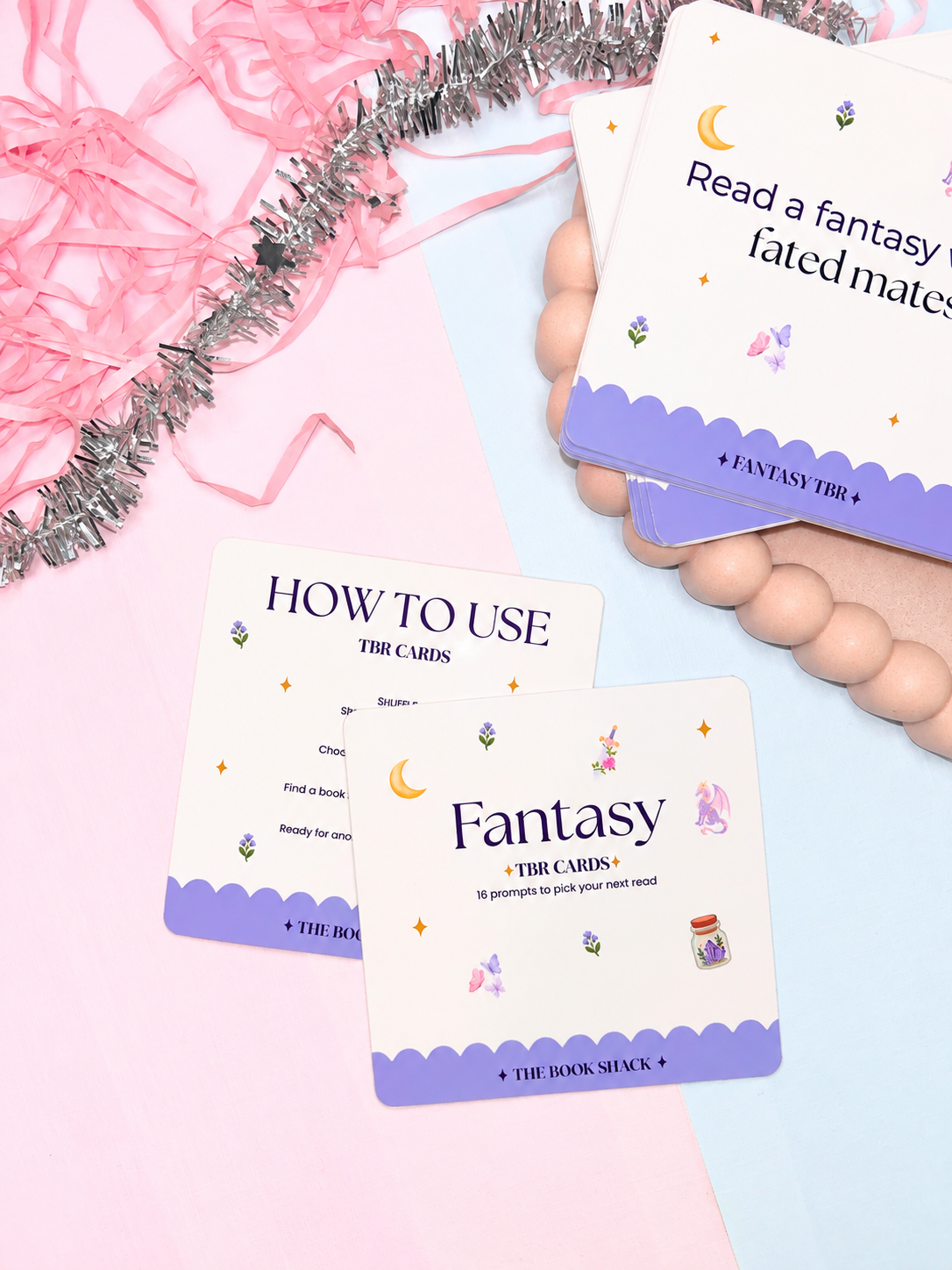 Hand holding Fantasy TBR card over How to Use card; purple illustrated reading prompts