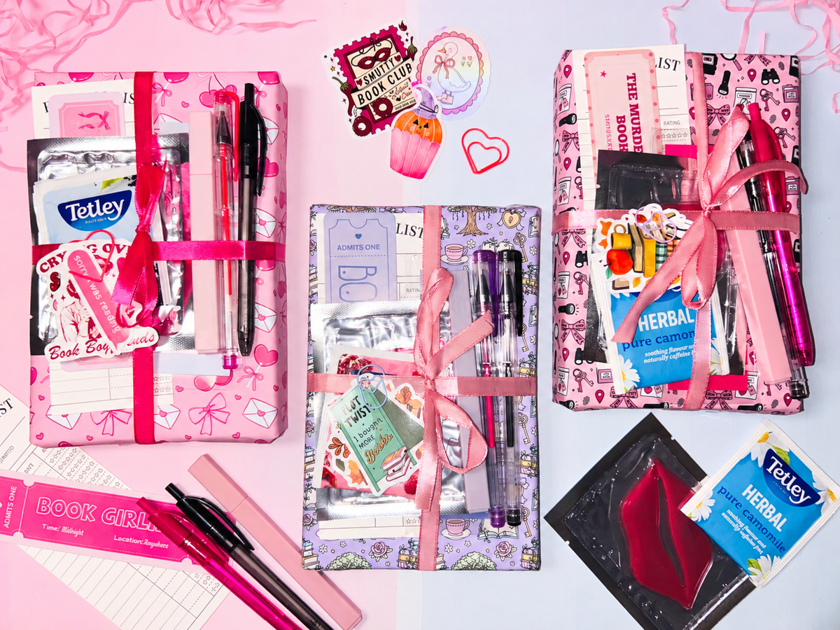 Pink mystery book gift bundle set with wrapped books, pens, and stationery accessories