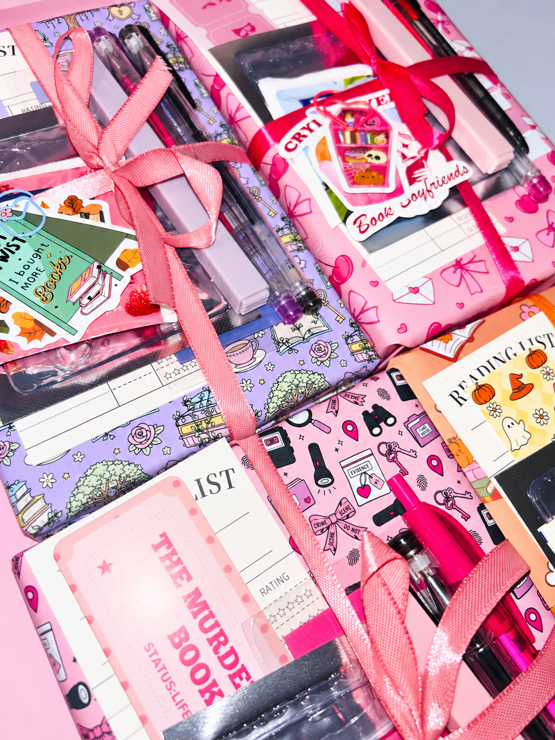 Pink wrapped book bundle with ribbons, pens, and notebook-style stationery