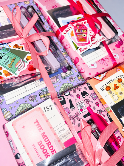 Pink wrapped book bundle with ribbons, pens, and notebook-style stationery