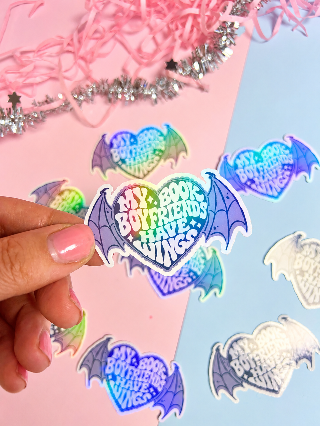 Holographic bat-wing sticker with “Book Boyfriends Have Wings” text, held by hand