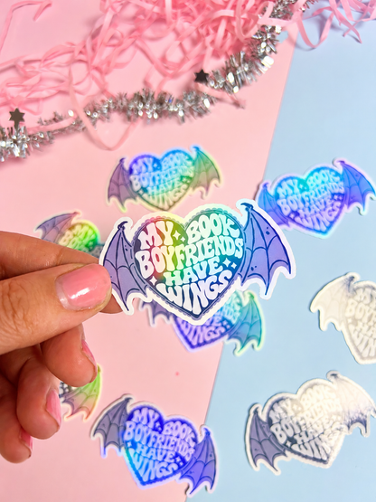 Holographic bat-wing sticker with “Book Boyfriends Have Wings” text, held by hand