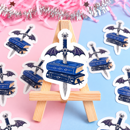 Sword and wings book stack sticker displayed on a small wooden easel