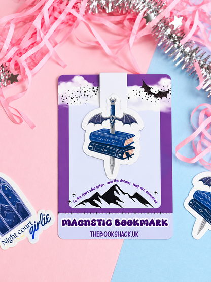 Magnetic bookmark card featuring blue dagger on stacked books with dark wings