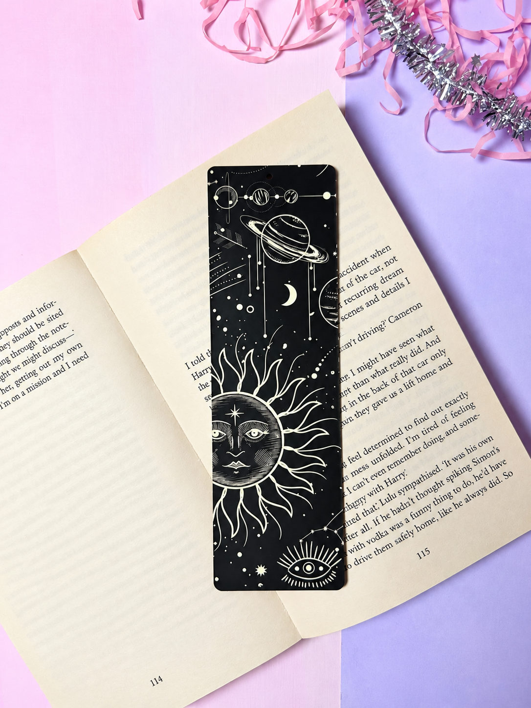Black celestial bookmark with white sun, planet orbit, and moon icons