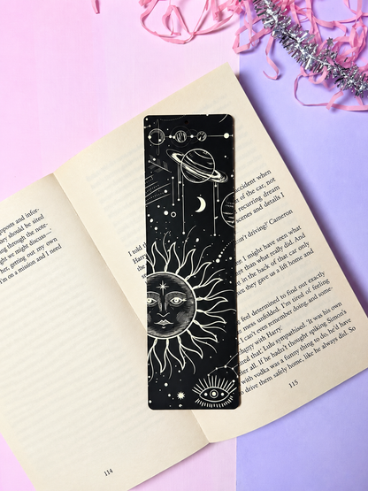 Black celestial bookmark with white sun, planet orbit, and moon icons