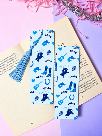 Cowboy-themed paper bookmark pair with blue patterned silhouettes and tassels