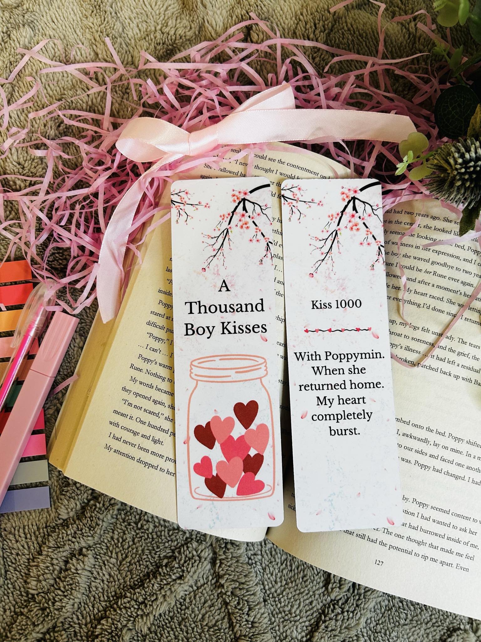 Romantic bookmarks inspired by the novel 'A Thousand Boy Kisses,' featuring cherry blossom branches, a heart-filled jar, and emotional quotes