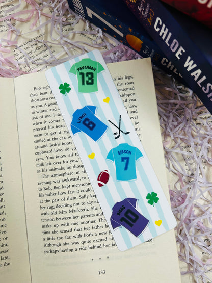 Bookmark with sports jersey designs labelled Kavanagh, Lynch, Gibson, and Biggs, laid over Binding 13 book.