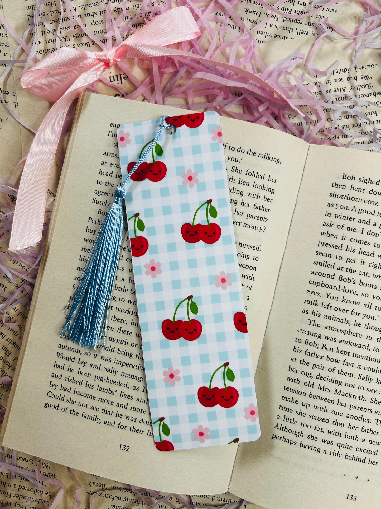 Set of colorful gingham bookmarks with fruit illustrations including cherries, strawberries, and citrus, placed on an open book.