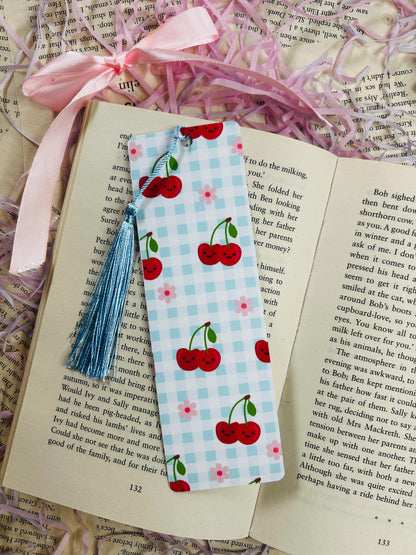 Set of colorful gingham bookmarks with fruit illustrations including cherries, strawberries, and citrus, placed on an open book.