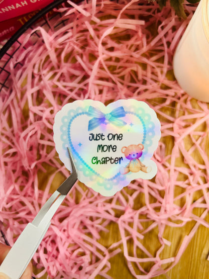 blue holographic sticker, with a love heart and teddy bear, featuring the quote 'just one more chapter'