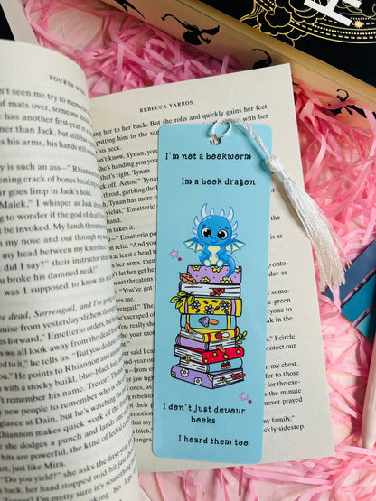 This updated bookmark now includes a delicate white tassel, adding a touch of elegance to the charming design. The whimsical dragon sitting atop a vibrant stack of books remains the focal point, paired with the playful quote: “I’m not a bookworm, I’m a book dragon. I don’t just devour books, I hoard them too.” The white tassel complements the light blue background, enhancing its appeal while maintaining functionality for avid readers