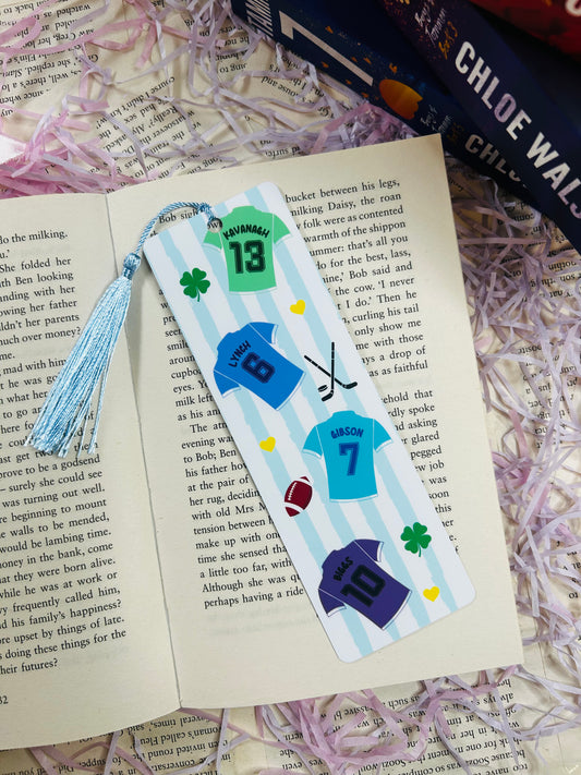 Bookmark with sports jersey designs labelled Kavanagh, Lynch, Gibson, and Biggs, laid over Binding 13 book.