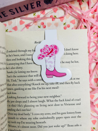 A pink magnetic bookmark featuring a cowgirl boot and hat design