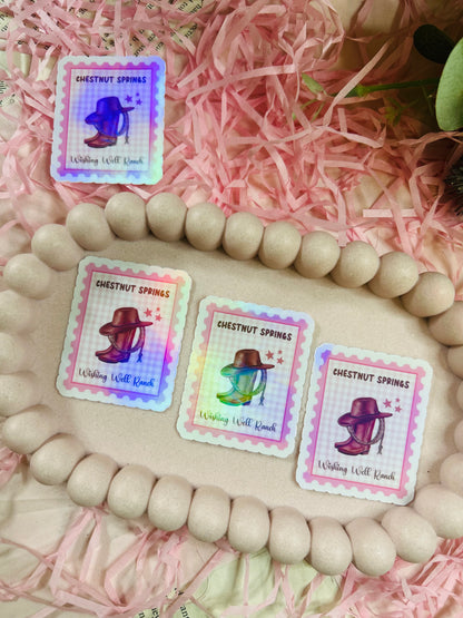 Holographic stamp-style sticker featuring a cowboy hat, lasso, and boots with the text "Chestnut Springs - Wishing Well Ranch" on a pastel gingham background.