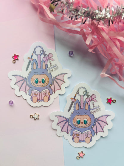 Two cute cartoon character stickers with bat wings on a pink and white background.