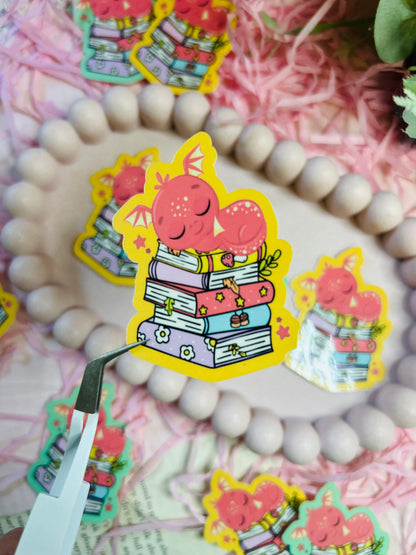  Red Dragon bookish stickers! Perfect for fantasy book lovers, this sticker features a charming red dragon perched on a stack of books.