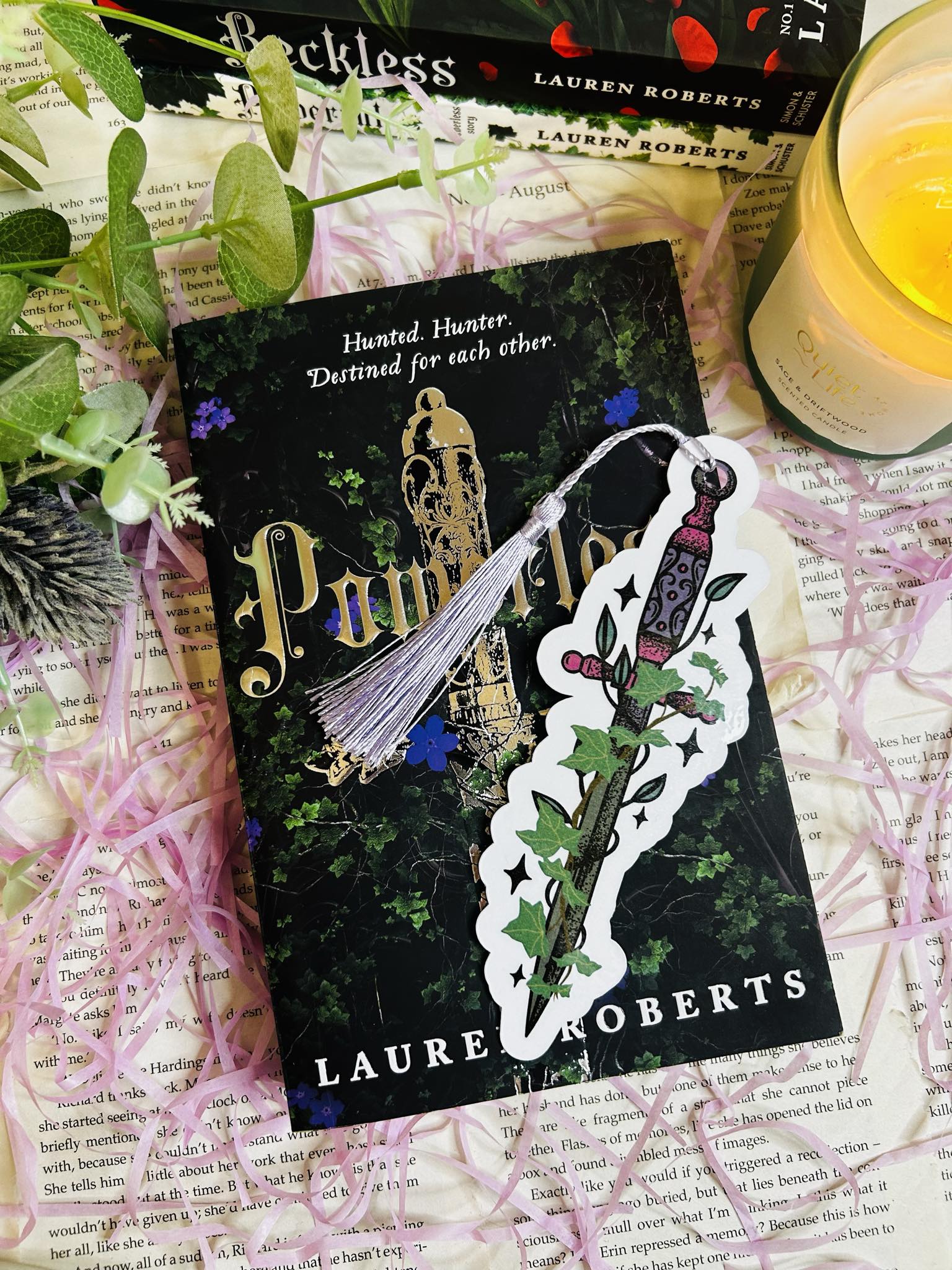 Die-cut bookmark shaped like a fantasy dagger entwined with ivy, perfect for dark fantasy and romantasy lovers, sat on top of Powerless book by Lauren roberts