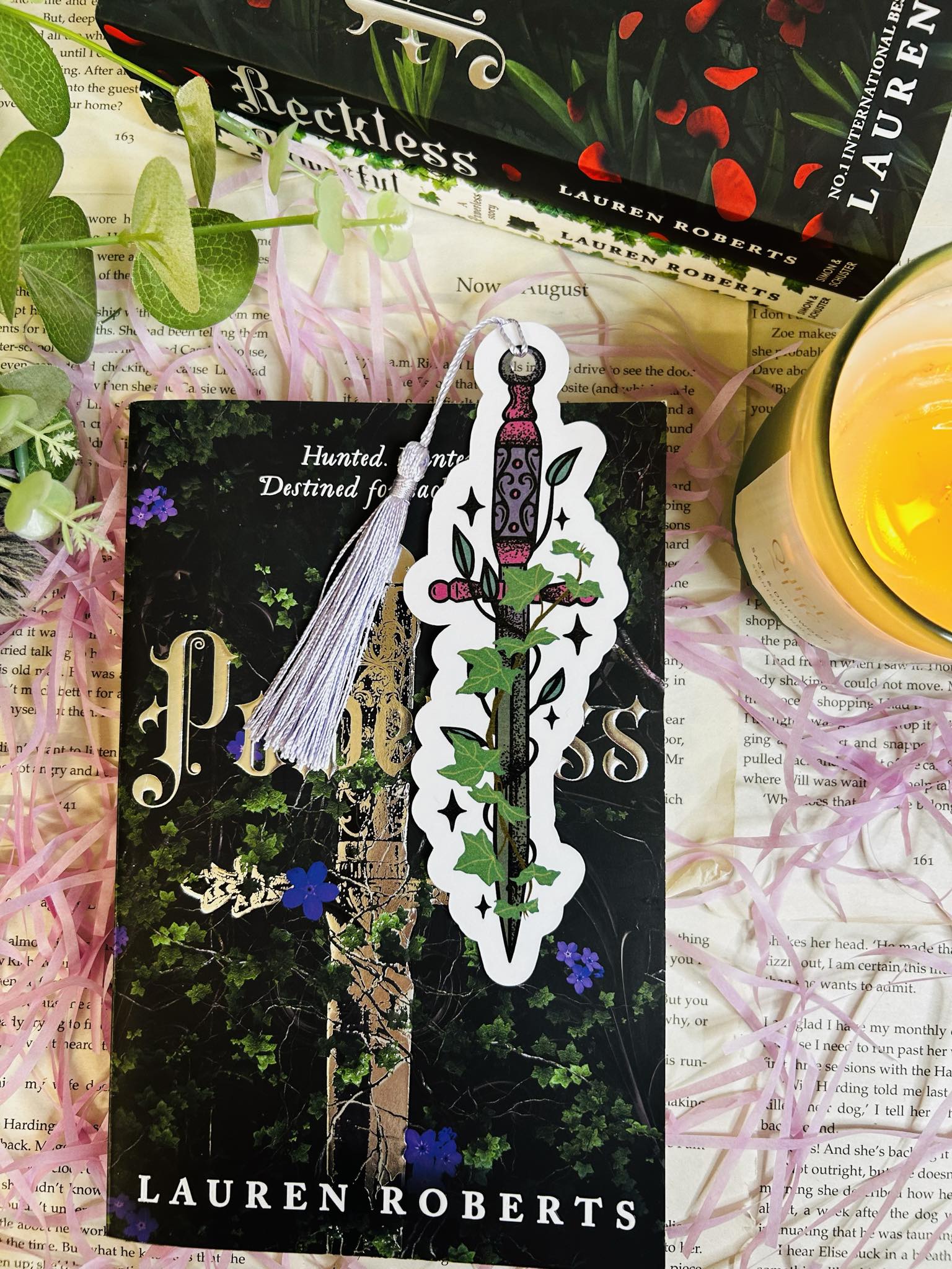 Die-cut bookmark shaped like a fantasy dagger entwined with ivy, perfect for dark fantasy and romantasy lovers, sat on top of Powerless book by Lauren roberts