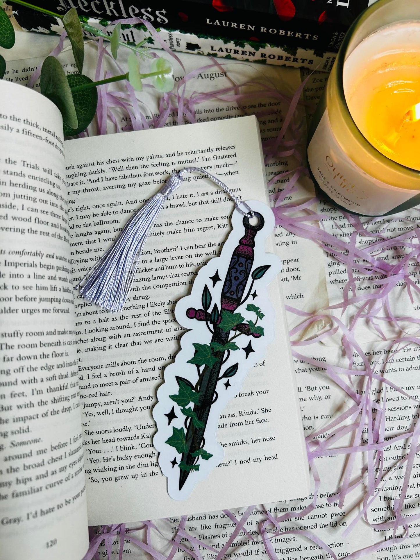 Die-cut bookmark shaped like a fantasy dagger entwined with ivy, perfect for dark fantasy and romantasy lovers, sat on top of Powerless book by Lauren roberts