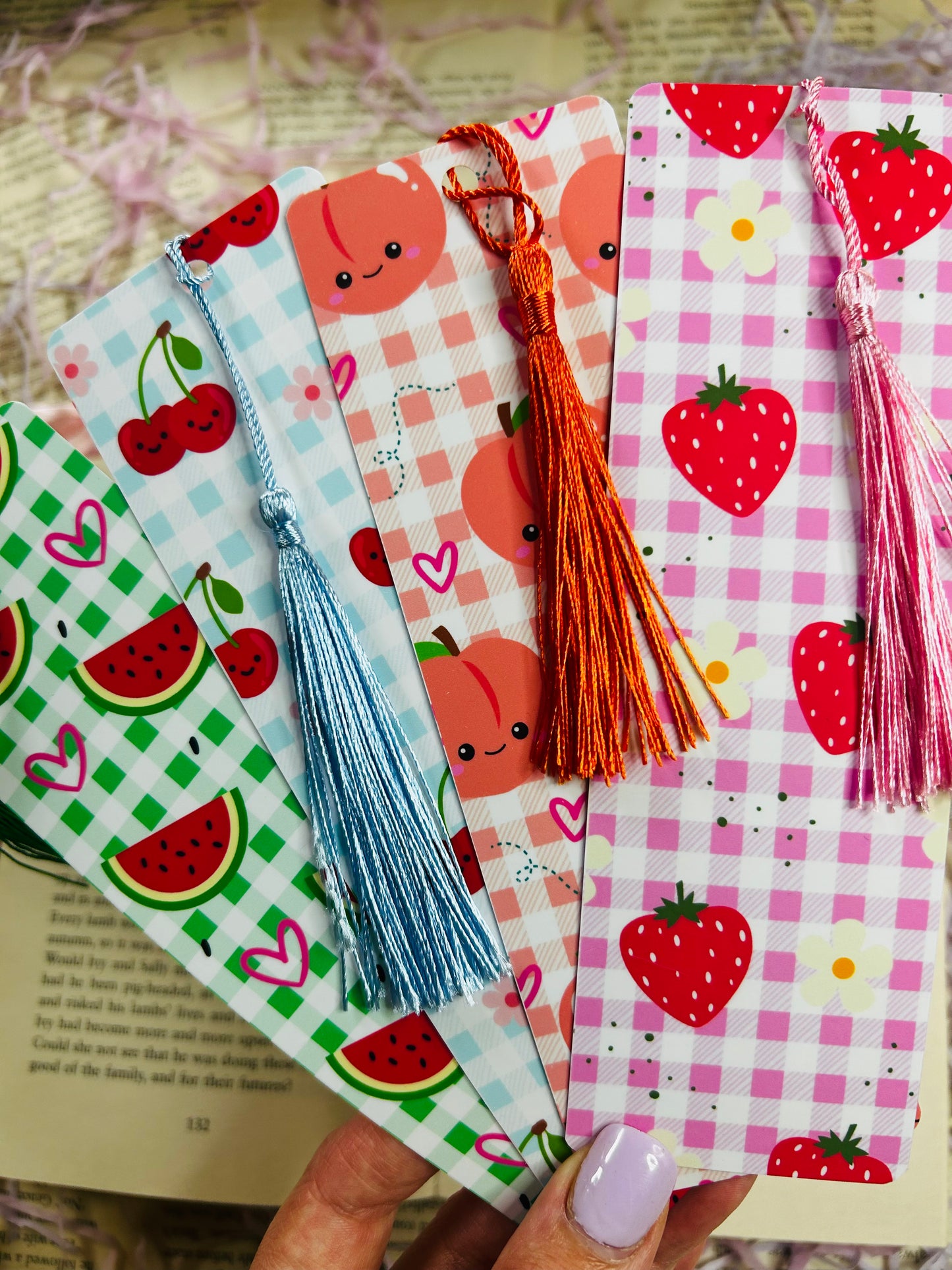 Set of colorful gingham bookmarks with fruit illustrations including cherries, strawberries, and citrus, placed on an open book.