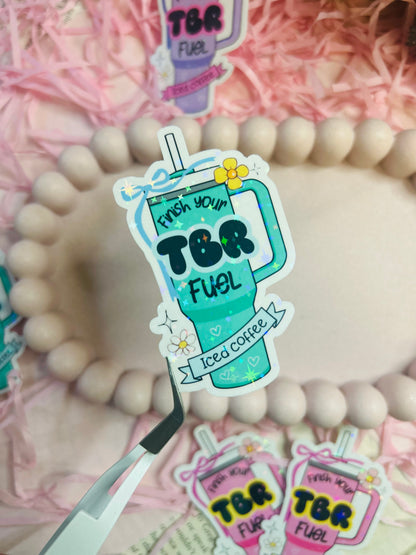 Pastel iced coffee bookish vinyl stickers with "Finish Your TBR Fuel" text, surrounded by pink shredded paper and decorative beads – perfect for readers and book lovers.