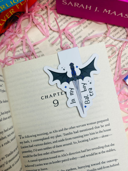 Bat-shaped bookmark on a book with pink ribbons and a visible title page.
