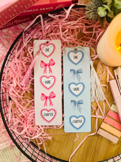 Pink and blue bookmarks with a heart and bow design featuring the quote ' One more chapter'